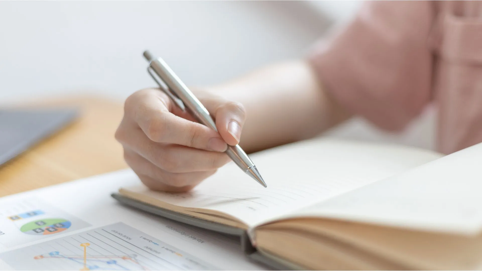 Žena píše perom na papier.