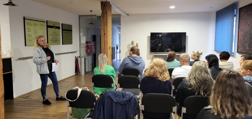 Na fotografii účastníci odborného podujatia: Prehĺbenie kompetencií učiteľov vo vzdelávaní v oblasti holokaustu Židov a genocídy Rómov, sediaci na stoličkách sledujúci prednášajúcu podujatia