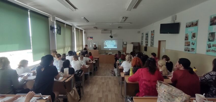 Na fotografii sú vzdelávajúci sa pedagógovia sediaci v školských laviciach a v pozadí stojaci prednášajúci