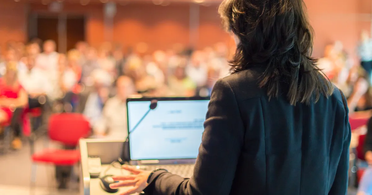 Žena rozpráva za pultom.