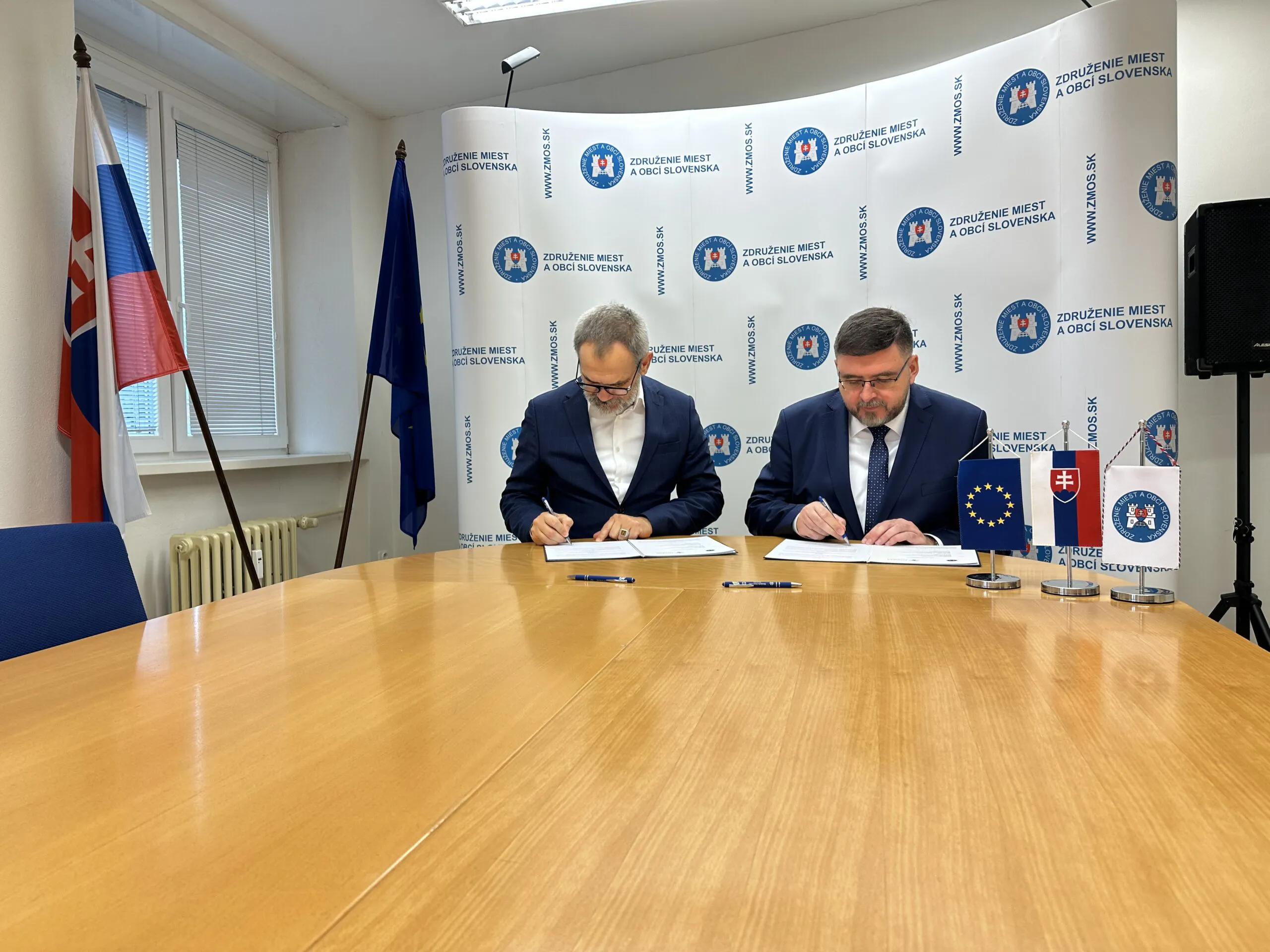 Dvaja muži podpisujú dokumenty.