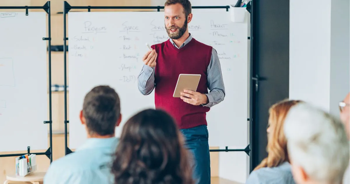 muž stojaci pred tabuľou vysvetľuje študentom