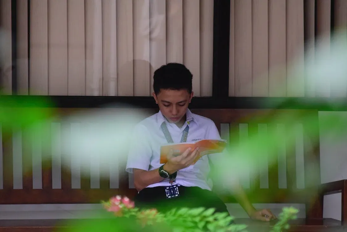 Chlapec číta tenkú knihu.