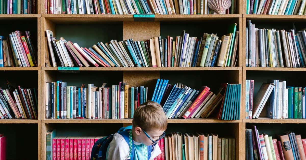 Na obrázku sa nachádza dieťa sediace na zemi, ktoré číta knihu.