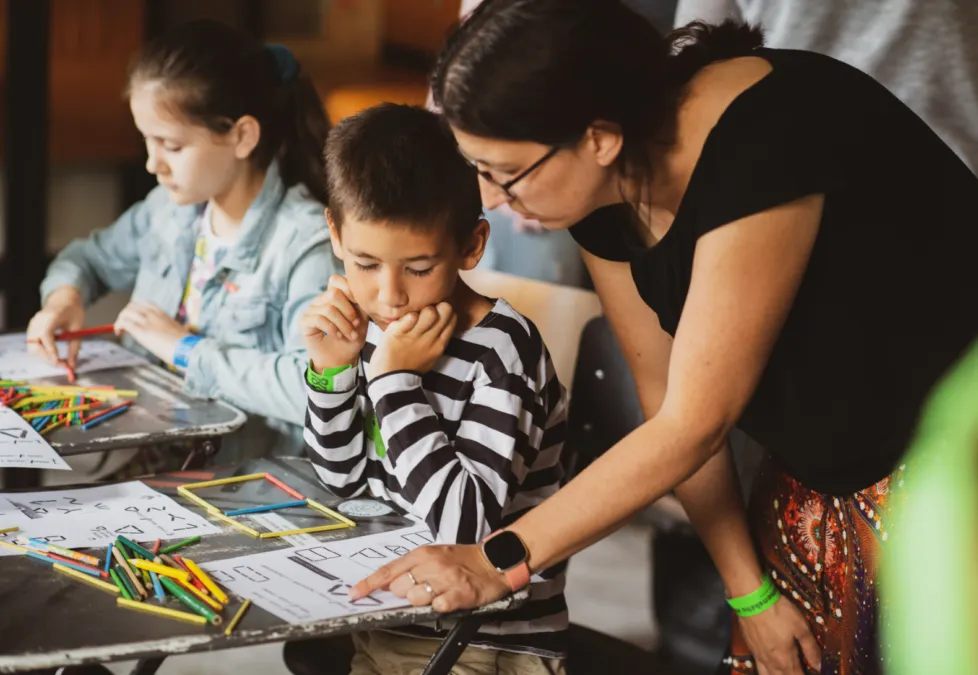 Na fotke učiteľka vysvetľuje žiakovi geometrické úlohy.