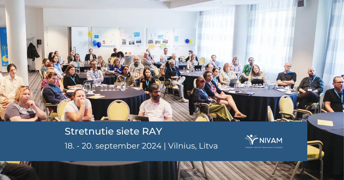 Ůčastníci diskusie sediaci na stoličkách pri okrúhlych stoloch.